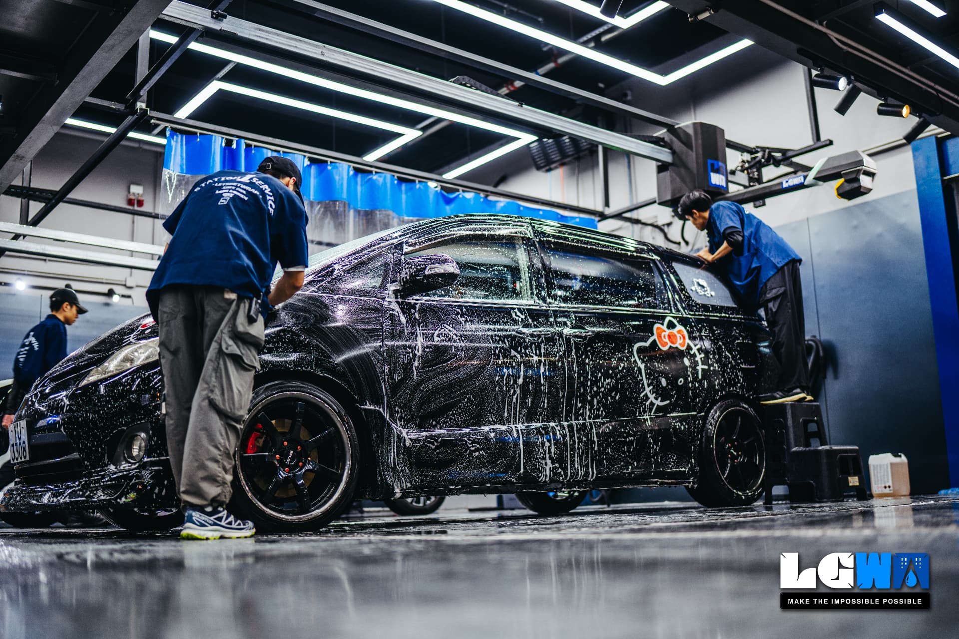 Lets Get Wash 室內工位內,工作人員以白色泡沫手洗一台黑色房車的實拍照